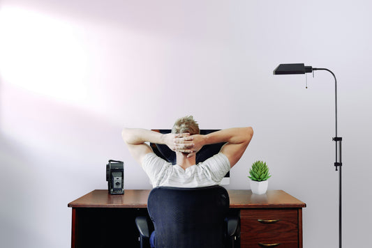 Relaxed man leaning back in chair, hands behind head in a serene home office