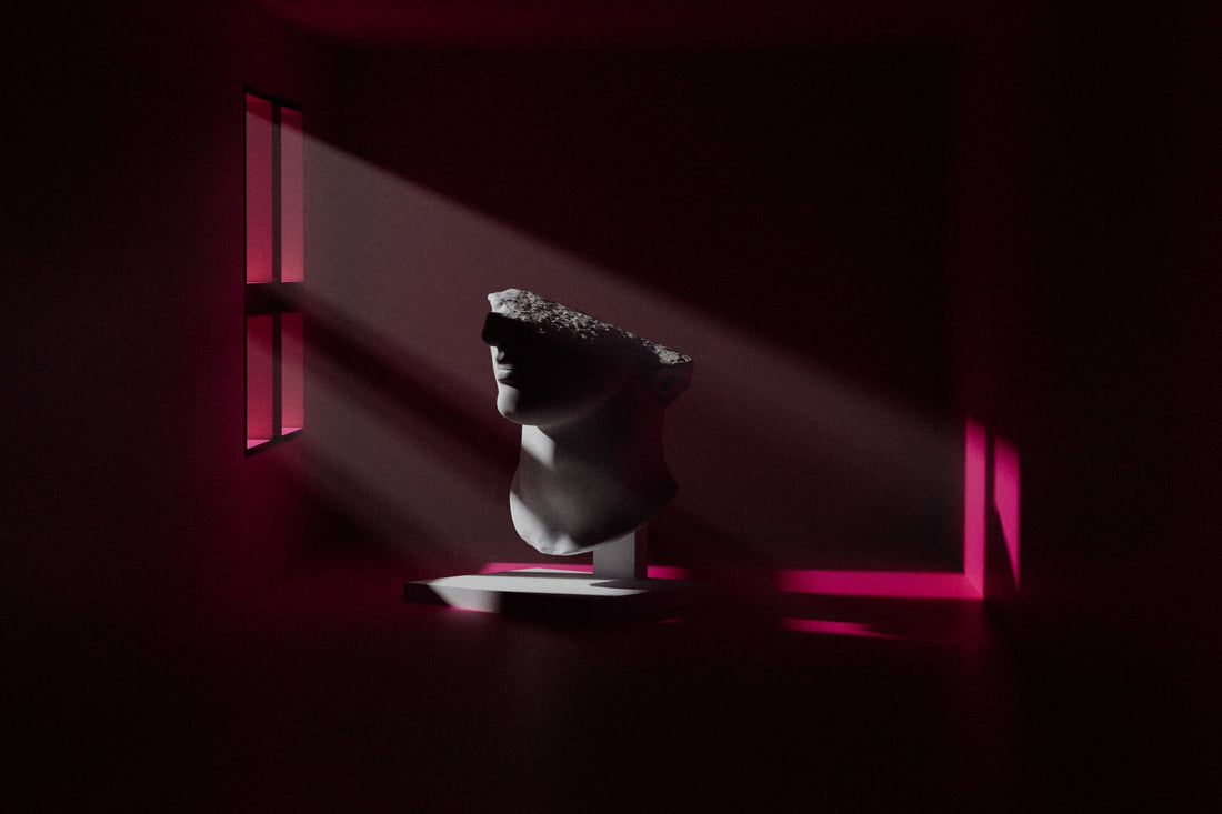 A classic sculpture head with a rough stone on top in a dim room with pink light